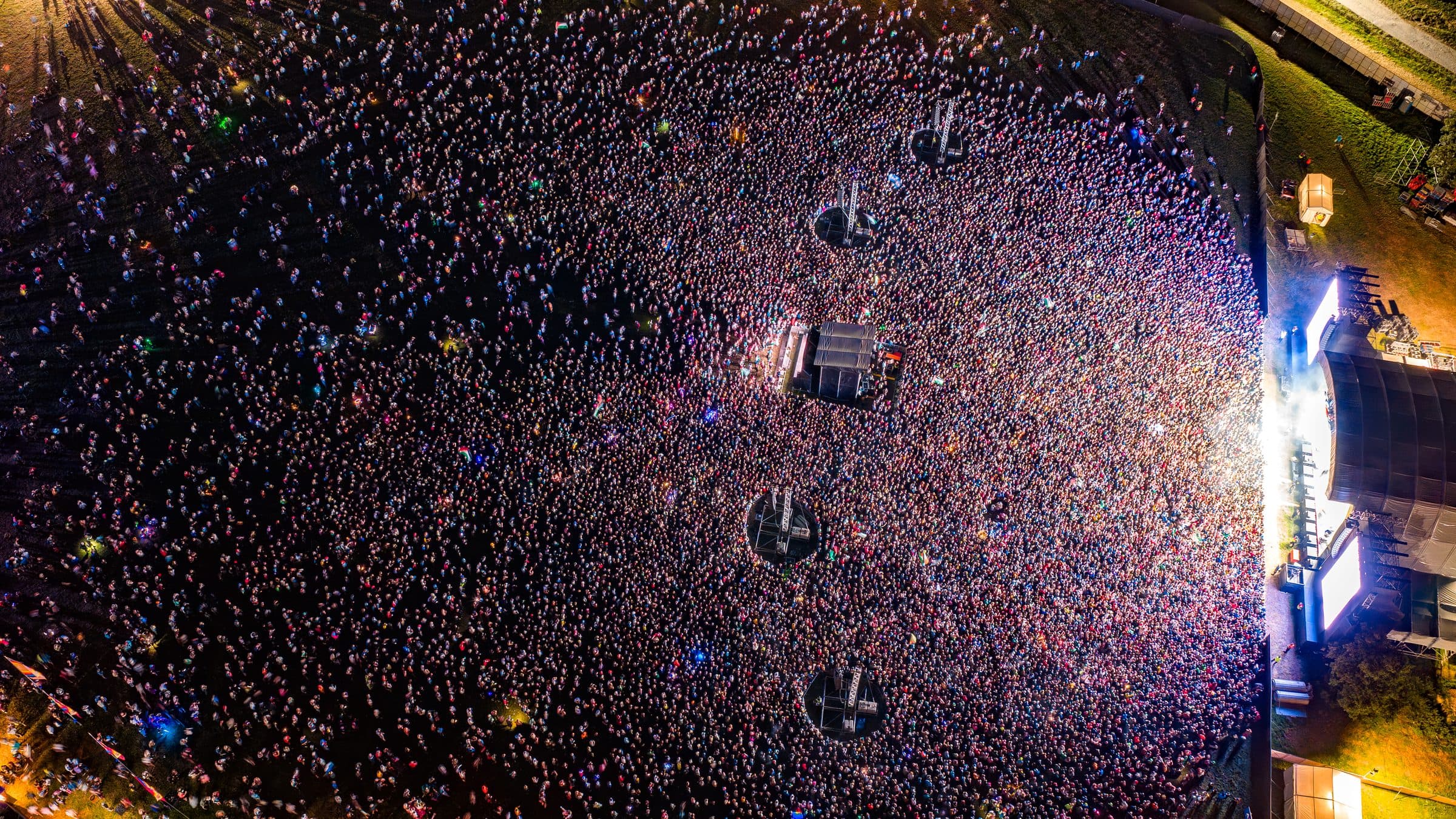 Top-down aerial view of a large festival crowd at night.